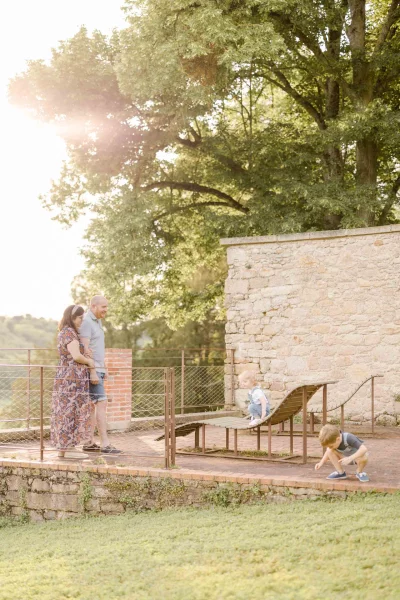 Mère enceinte en robe fleurie observant son enfant jouer près d'un château au soleil